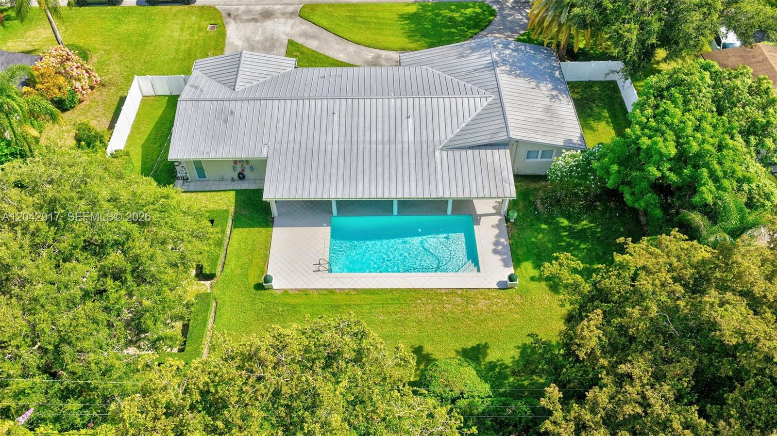 An aerial view of a single-story house with a metal roof and a backyard pool — 7240 SW 131st St, Pinecrest FL 33156, PINECREST, FL