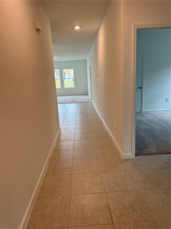 A tiled hallway leads toward a living area with carpeted floors and large windows — 2210 RAVEN RIDGE ROAD, MINNEOLA, FL