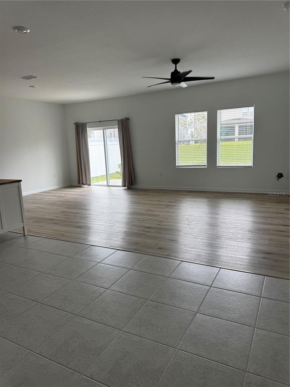 An open-concept living area features light wood-look flooring, a ceiling fan, and sliding glass doors — 2210 RAVEN RIDGE ROAD, MINNEOLA, FL