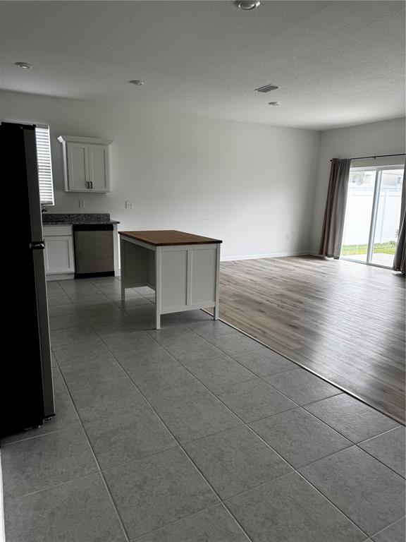 A kitchen with a small island and tile flooring transitions into a living area with wood-look floors — 2210 RAVEN RIDGE ROAD, MINNEOLA, FL