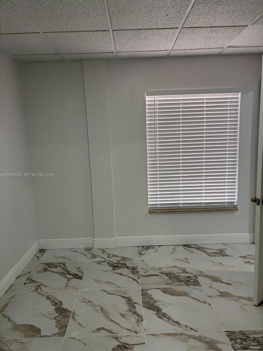 A room with white walls, a window with blinds, and marble-patterned tile flooring — 5327 Commercial Way # B105, FL 34606, FL