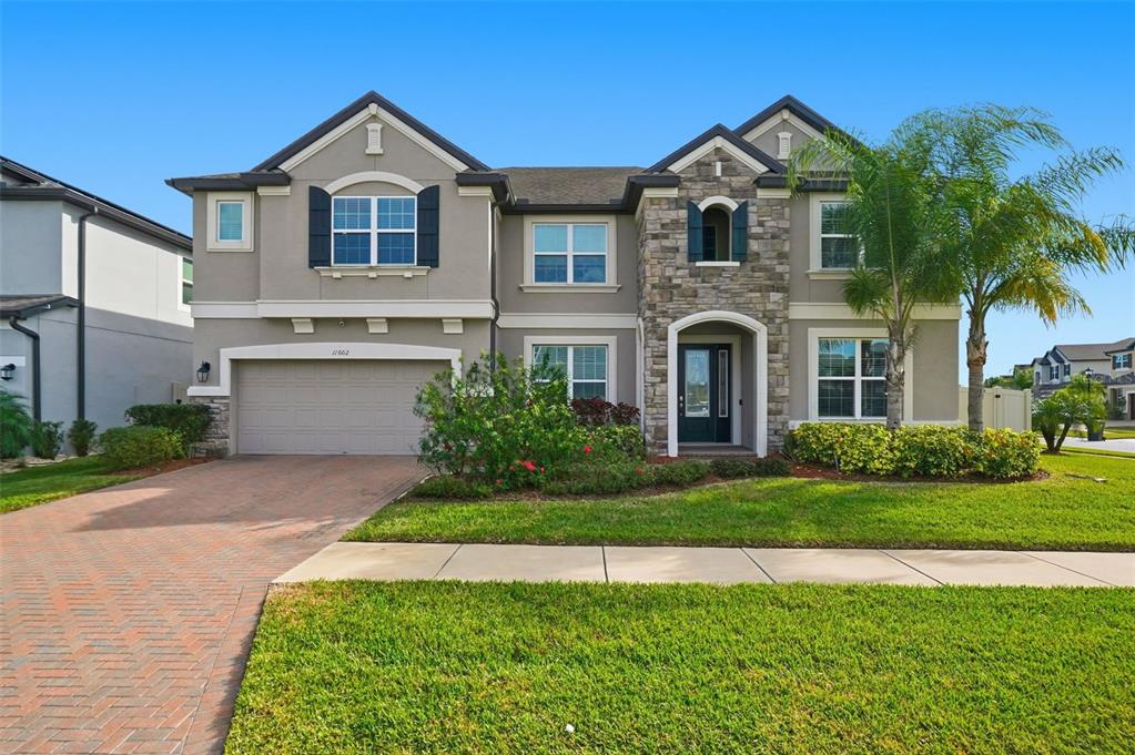 A two-story suburban house with a stone facade, a two-car garage, and a palm tree — 11002 SUNDRIFT DRIVE, TAMPA, FL