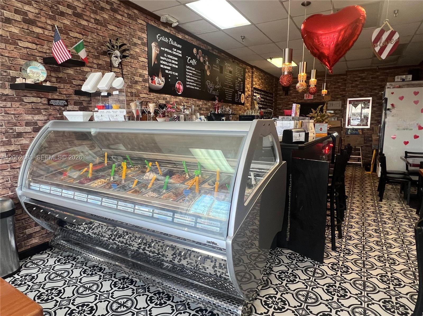 A gelato shop features a glass display case, brick walls, and patterned tile flooring — KENDALL, FL