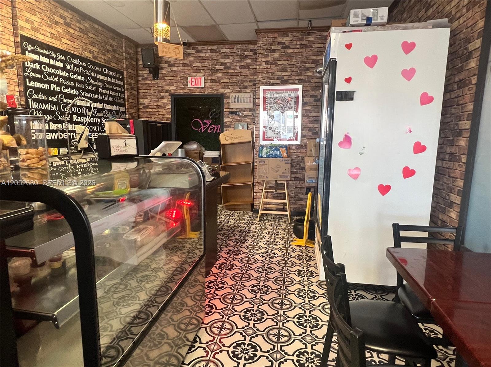 An interior view of a gelato shop featuring brick walls, patterned tile floors, and a display case — KENDALL, FL