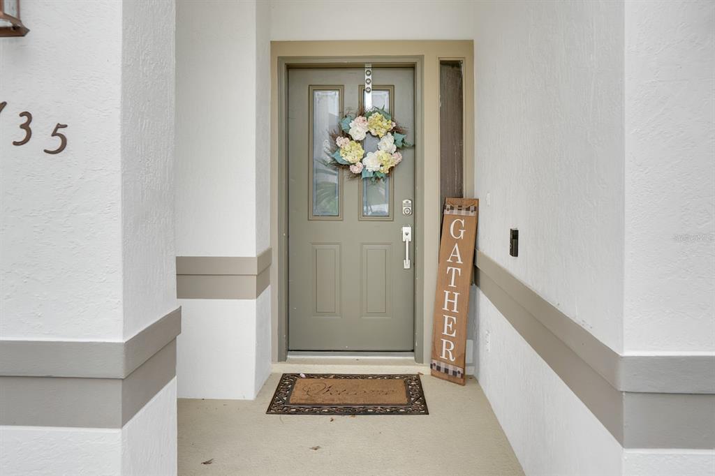 A front entryway features a sage green door with a floral wreath and a welcome mat — 2735 SCARBOROUGH DRIVE, KISSIMMEE, FL