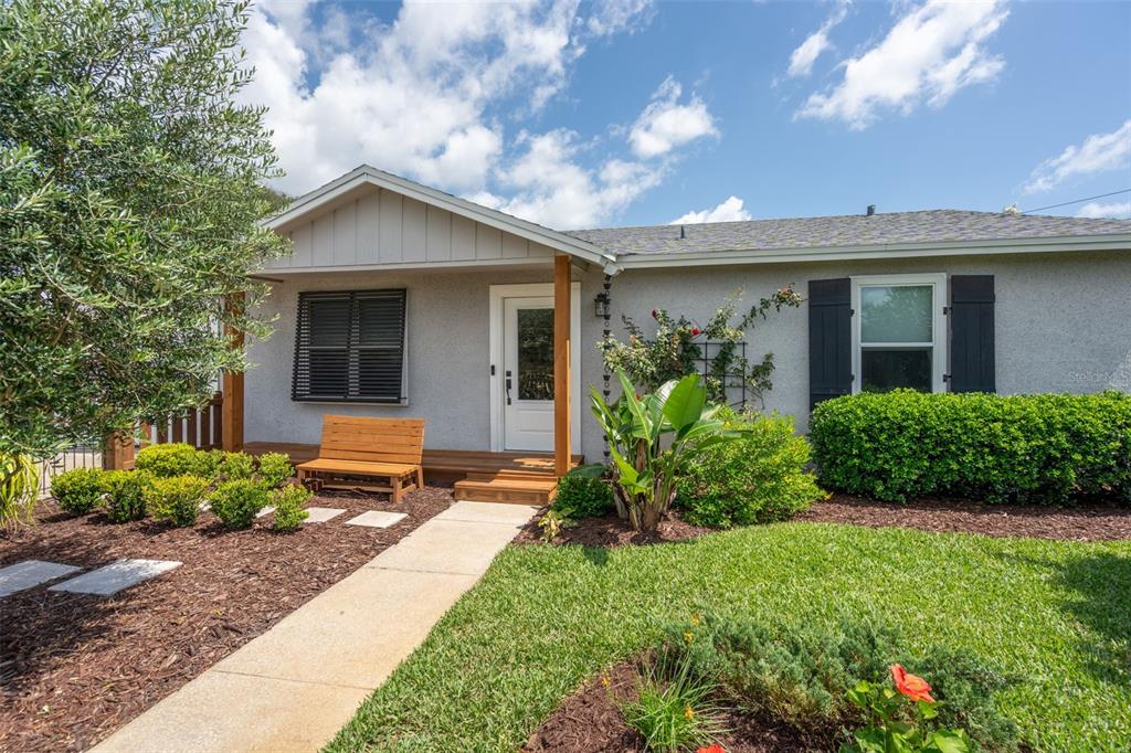 A single-story house with a gray stucco exterior, a wooden porch, and a front walkway — 208 TRADE WIND LANE, ST AUGUSTINE BEACH, FL
