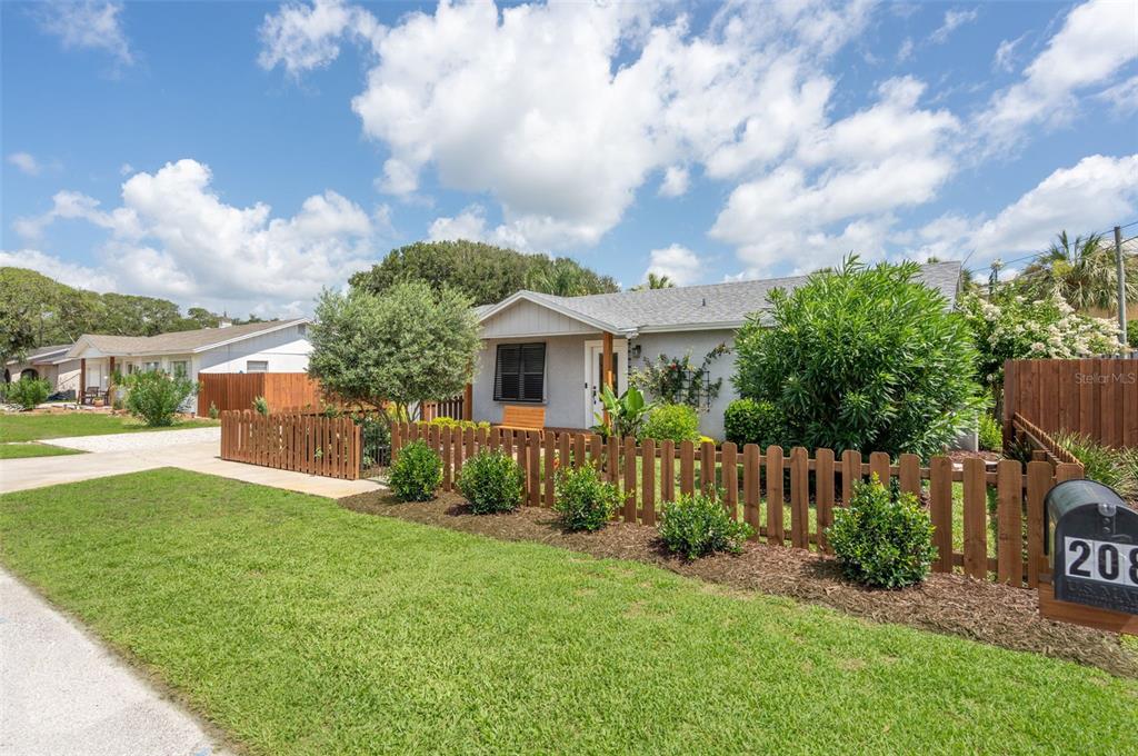 A single-story house with a wooden picket fence and a green lawn in front — 208 TRADE WIND LANE, ST AUGUSTINE BEACH, FL