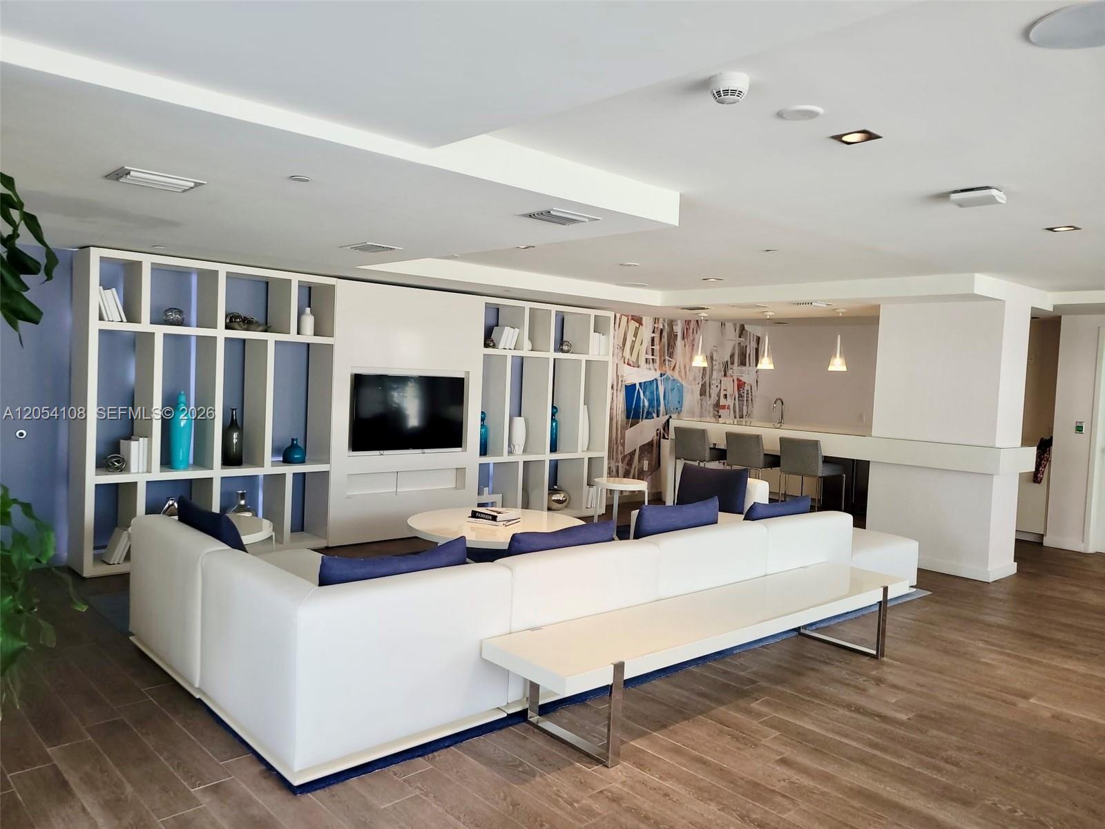 A modern living room features a white sectional sofa, built-in shelving, and a kitchen bar — 4250 Biscayne Blvd # 806, Miami FL 33137, MIAMI, FL