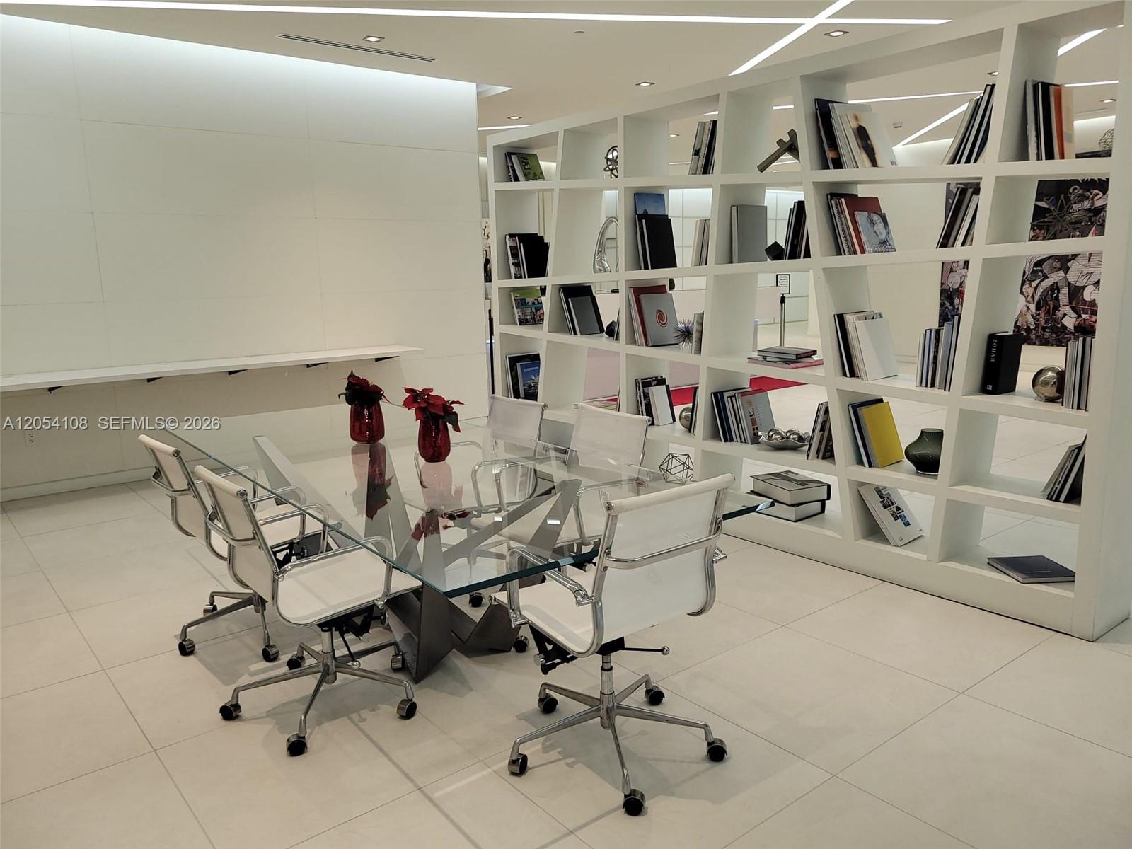 A modern office space features a glass conference table, white chairs, and a large bookshelf — 4250 Biscayne Blvd # 806, Miami FL 33137, MIAMI, FL