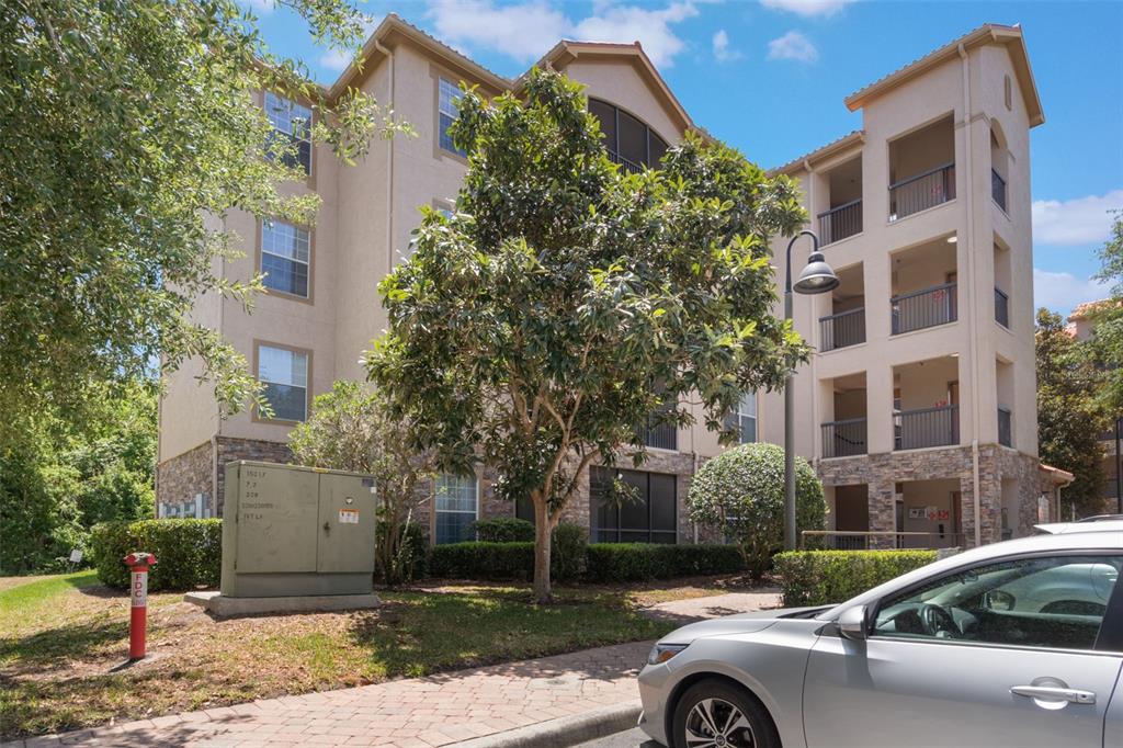 A multi-story apartment building with a stone facade, balconies, and a fire hydrant nearby — 1375 TUSCANA LANE UNIT 1207, DAVENPORT, FL
