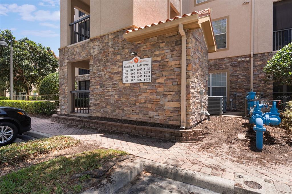 Exterior view of a stone-clad apartment building entrance with a unit directory sign — 1375 TUSCANA LANE UNIT 1207, DAVENPORT, FL