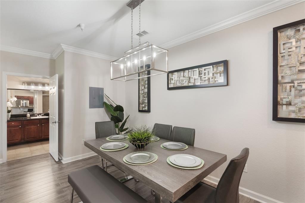 A dining room features a gray wooden table, chairs, a bench, and a rectangular light fixture — 1375 TUSCANA LANE UNIT 1207, DAVENPORT, FL