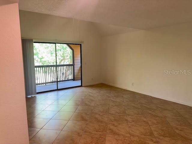 An empty room features tile flooring, vaulted ceilings, and a sliding glass door to a balcony — 365 FORESTWAY CIRCLE UNIT 303, ALTAMONTE SPRINGS, FL