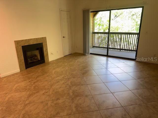 A living room with tile flooring, a fireplace, and a sliding glass door to a balcony — 365 FORESTWAY CIRCLE UNIT 303, ALTAMONTE SPRINGS, FL