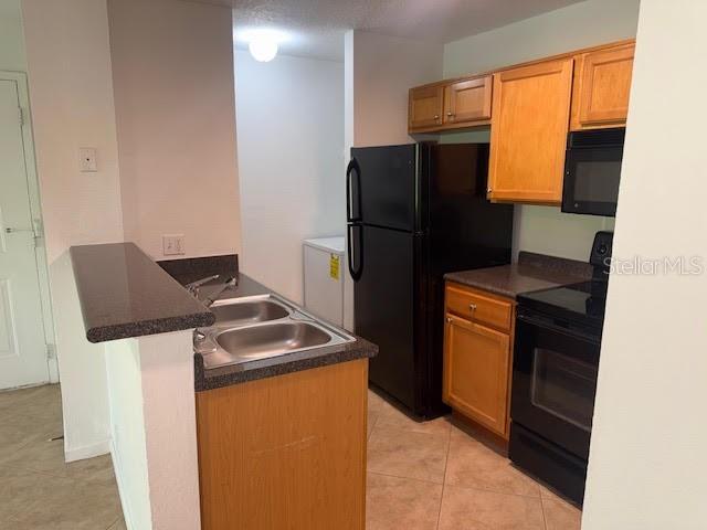 A kitchen features light wood cabinets, black appliances, and a double-basin sink on a peninsula — 365 FORESTWAY CIRCLE UNIT 303, ALTAMONTE SPRINGS, FL