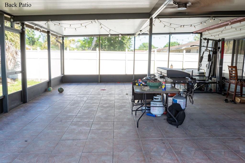 A screened-in back patio features tiled flooring, string lights, and a grill area — 8204 TRAMMELL TRAIL, TAMPA, FL