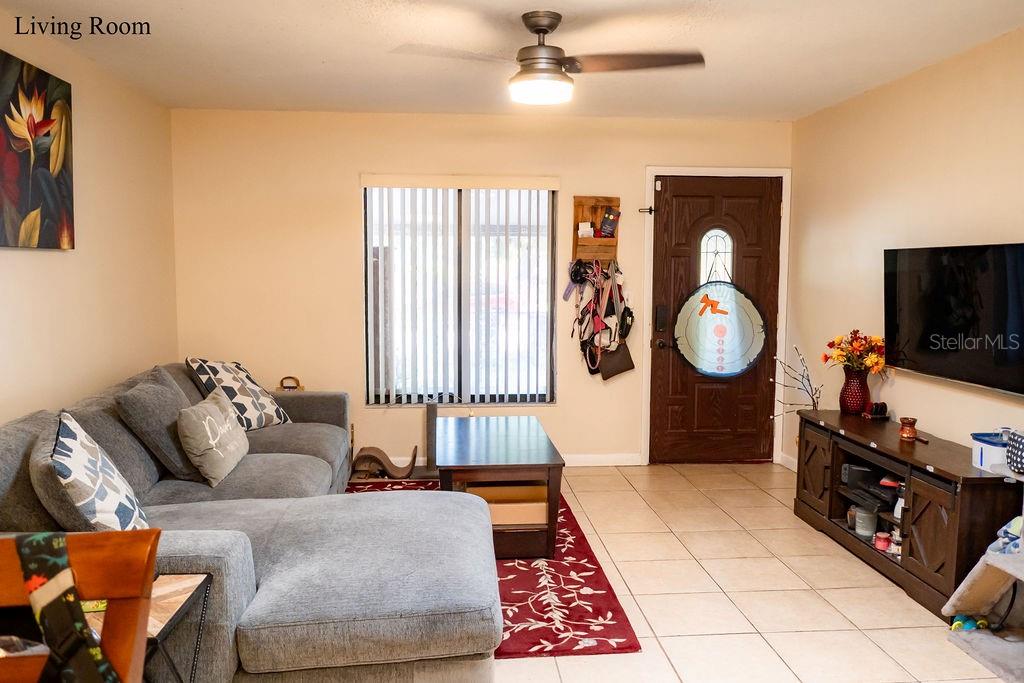 A living room features a gray sectional sofa, a coffee table, and a wall-mounted television — 8204 TRAMMELL TRAIL, TAMPA, FL