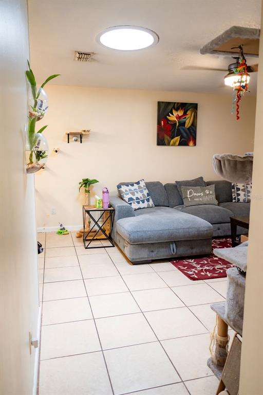 A living room features a gray sectional sofa, tiled floors, and a circular skylight — 8204 TRAMMELL TRAIL, TAMPA, FL
