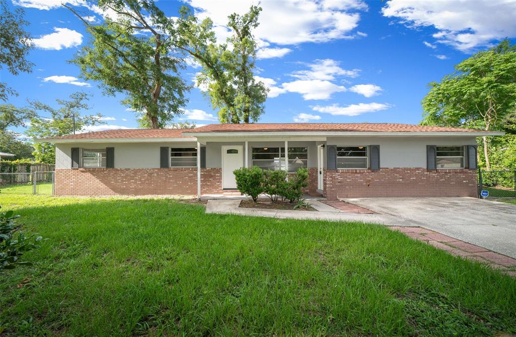A single-story house with a brick and gray siding exterior, a front lawn, and driveway — 2100 NE 52ND STREET, OCALA, FL
