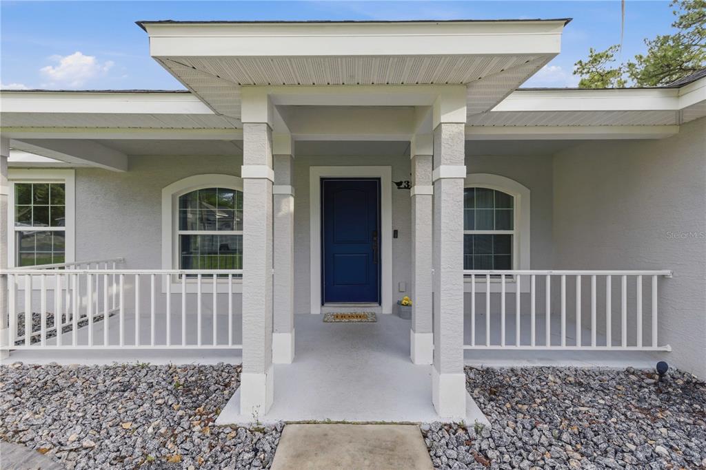 A front entrance features a blue door, a covered porch with white railings, and gravel landscaping — 35 SPECEBERRY CIRCLE, HOMOSASSA, FL