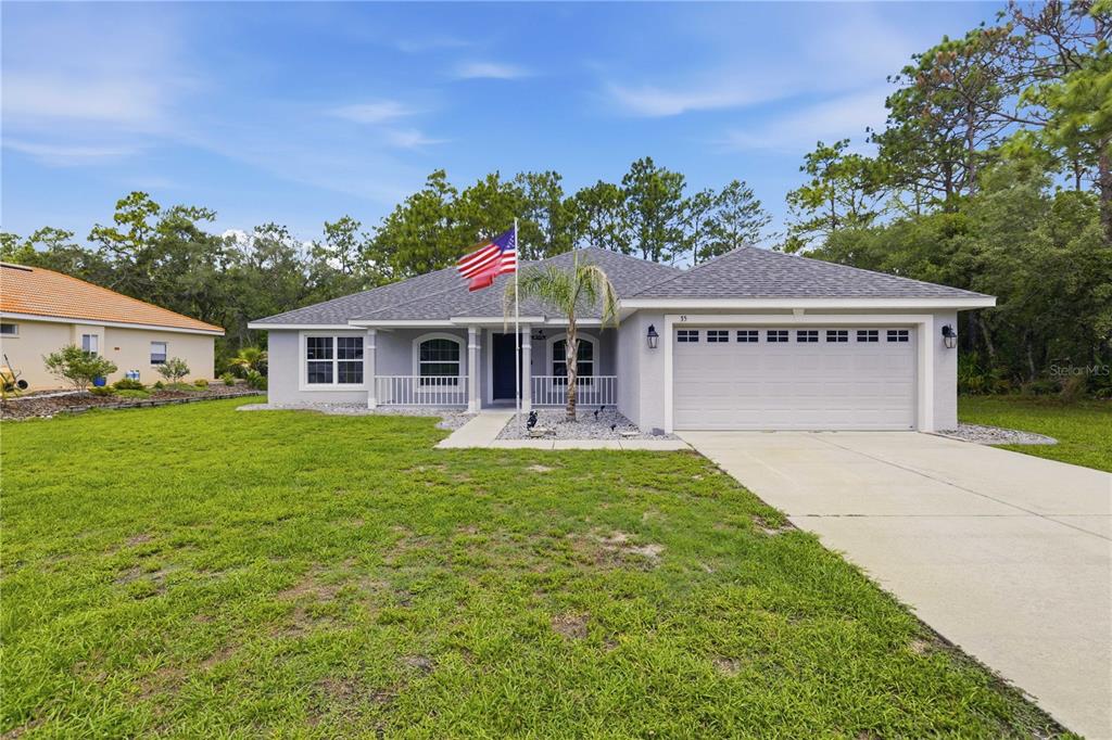 A single-story house with a gray exterior, a two-car garage, and an American flag — 35 SPECEBERRY CIRCLE, HOMOSASSA, FL