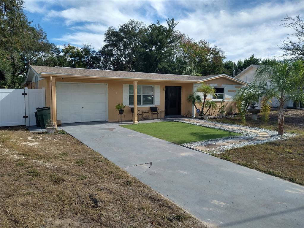 A single-story house with a garage, concrete driveway, and a small front yard — 12910 COLLEGE HILL DRIVE, HUDSON, FL