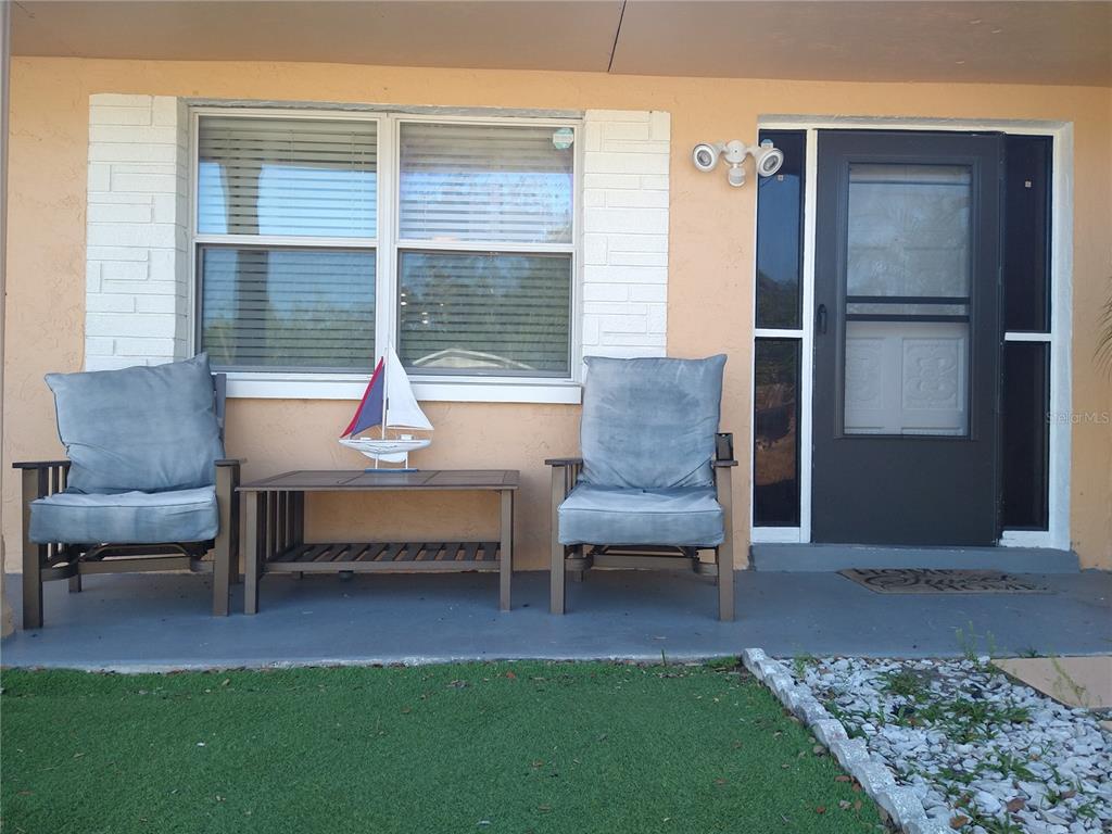 A front porch features two gray chairs, a small table with a sailboat, and a door — 12910 COLLEGE HILL DRIVE, HUDSON, FL
