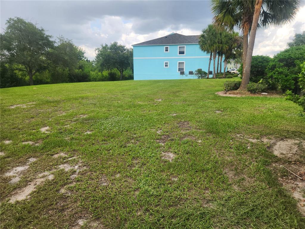 A grassy, vacant lot sits in front of a bright blue two-story building — 3134 SUN LAKE COURT UNIT B, KISSIMMEE, FL