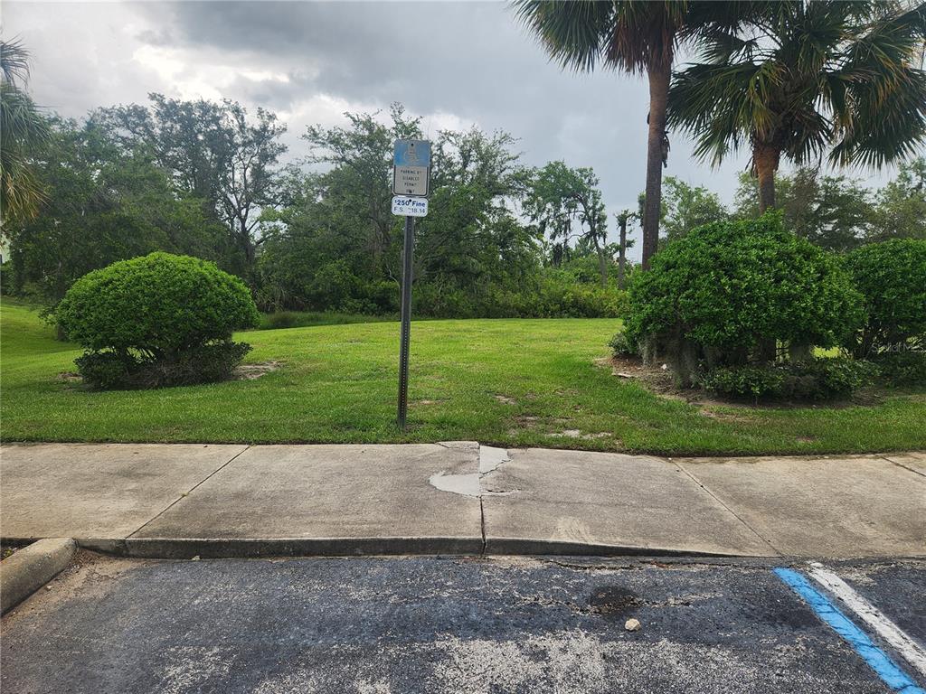 A grassy lot features a handicap parking sign and a sidewalk in the foreground — 3134 SUN LAKE COURT UNIT B, KISSIMMEE, FL