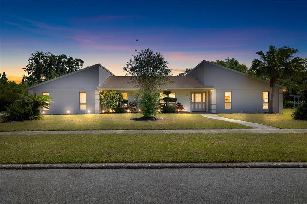 A single-story house with a symmetrical facade, a central entrance, and exterior landscape lighting — 34 MISTY MEADOW LANE, MULBERRY, FL