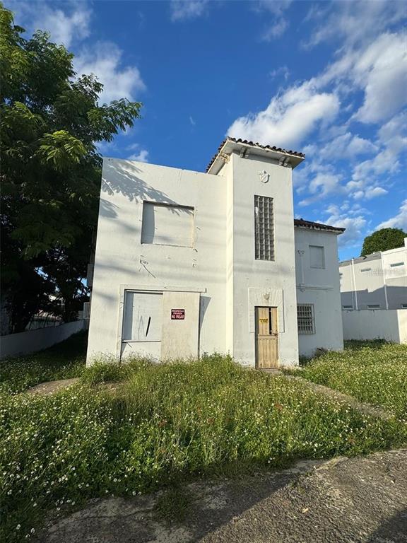 A two-story white stucco building with boarded-up windows and a central tower stands outdoors — 39 AVENIDA MAYAGUEZ, SAN JUAN, PR