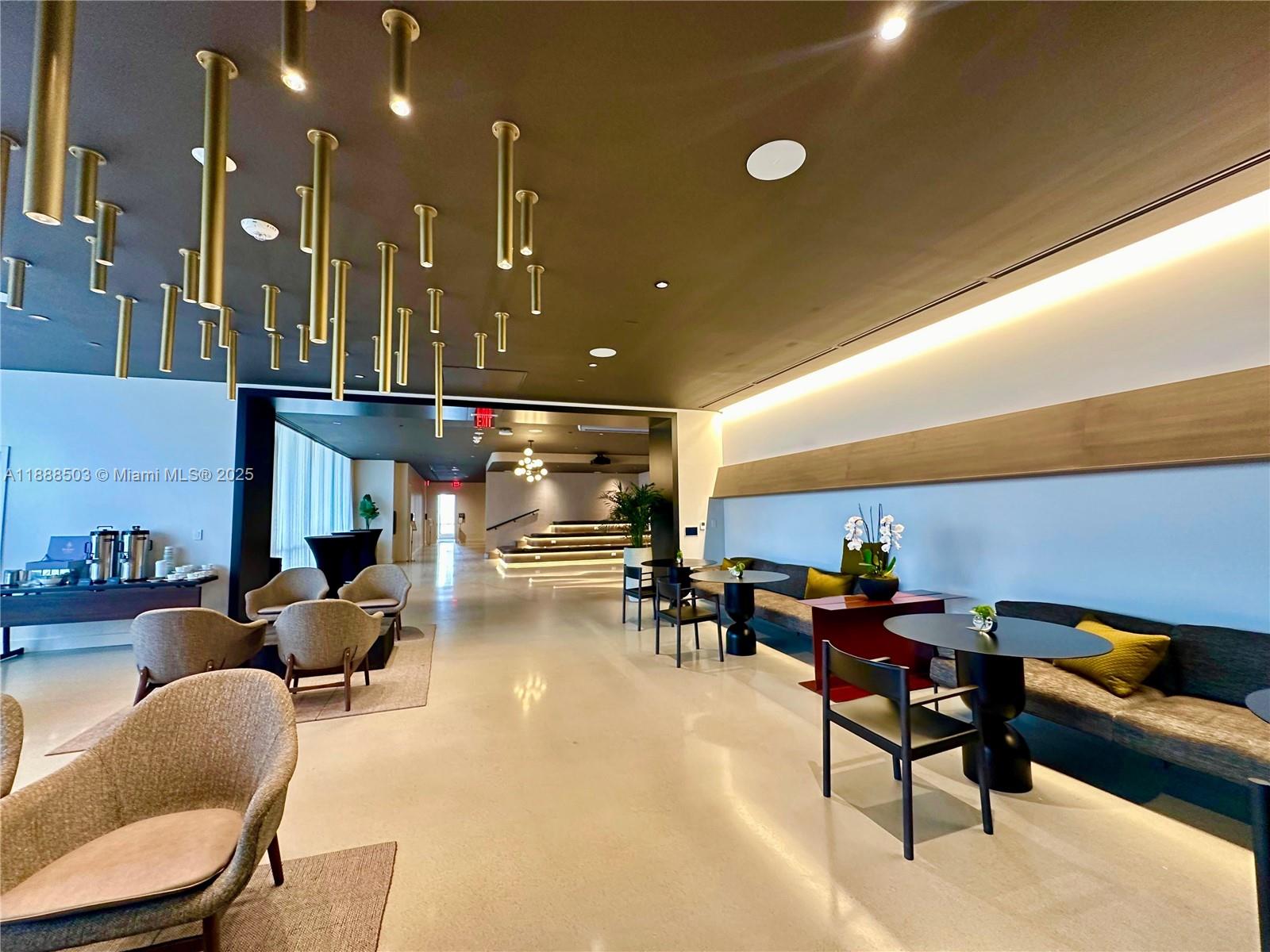 A modern lounge area features pendant tube lighting, circular tables, and upholstered seating — 159 NE 6th St # 3306, Miami FL 33132, MIAMI, FL