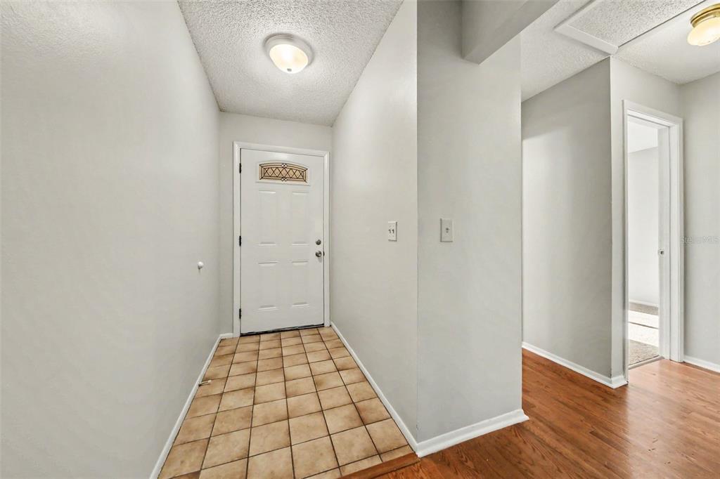 An entryway features a white front door, tiled flooring, and light gray walls — 7734 LAKESIDE WOODS DRIVE, ORLANDO, FL