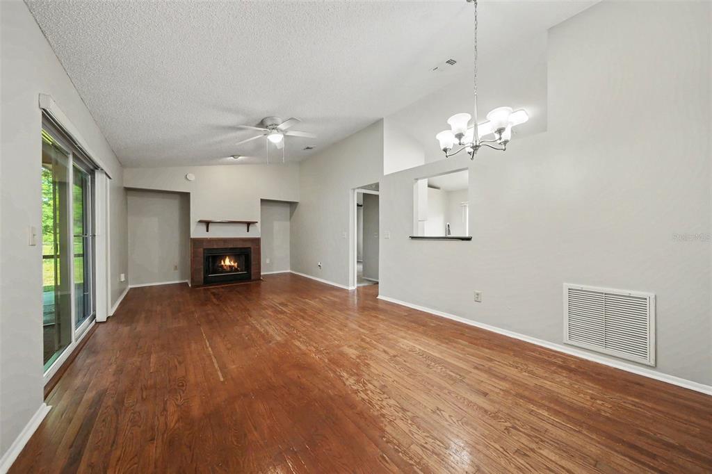 A living room with wood flooring, a fireplace, a ceiling fan, and a chandelier — 7734 LAKESIDE WOODS DRIVE, ORLANDO, FL