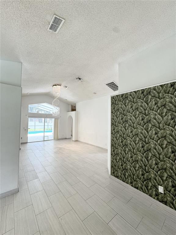 An open living area features light tile floors, a vaulted ceiling, and a leaf-patterned accent wall — 2627 ONEIDA LOOP, KISSIMMEE, FL