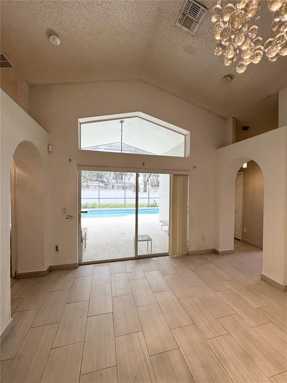 A living room with vaulted ceilings, tile flooring, and a sliding glass door to a pool — 2627 ONEIDA LOOP, KISSIMMEE, FL