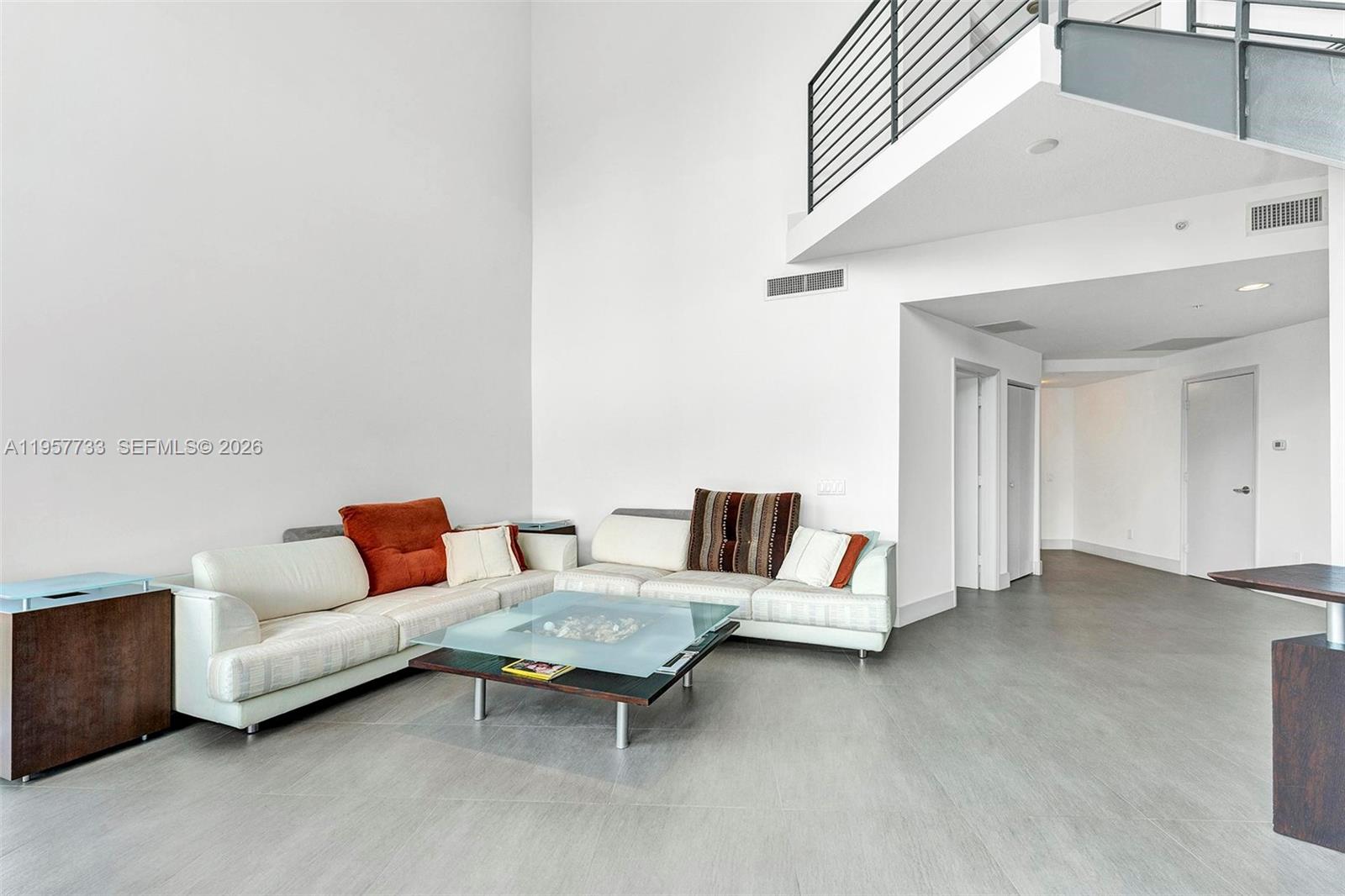 A living room features white walls, high ceilings, a sectional sofa, and tile flooring — 60 SW 13th St # 3400, Miami FL 33130, MIAMI, FL