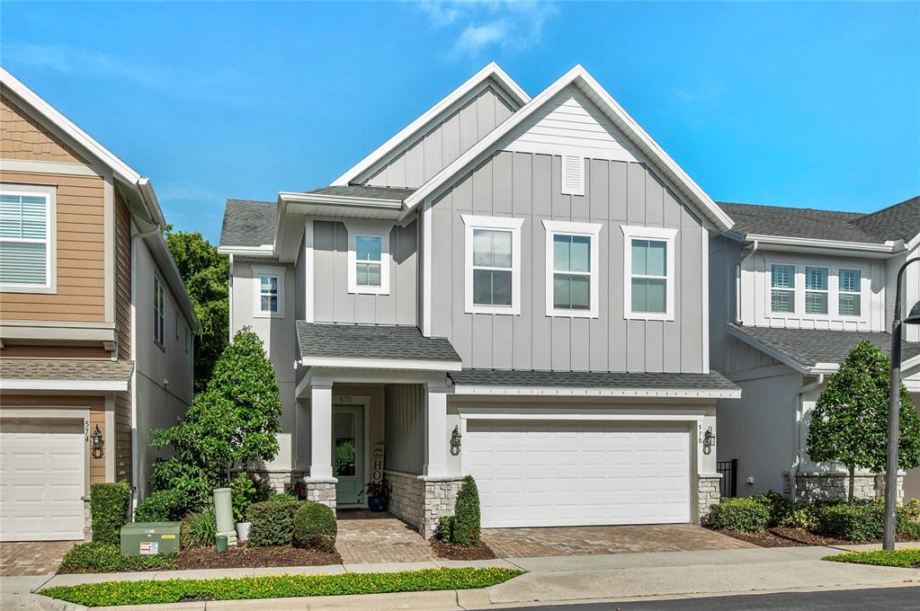 A two-story house with gray vertical siding, a stone base, and a two-car garage — 570 WISHBONE LANE, LAKE MARY, FL