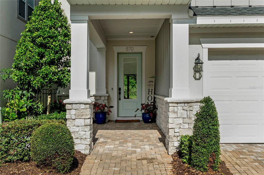The exterior front entrance features a light green door, stone pillars, and a paved walkway — 570 WISHBONE LANE, LAKE MARY, FL