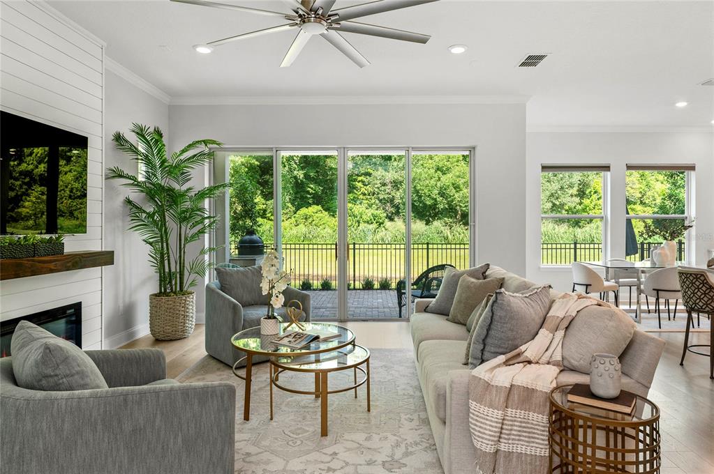 A living room features a fireplace, gray furniture, a ceiling fan, and sliding glass doors — 570 WISHBONE LANE, LAKE MARY, FL