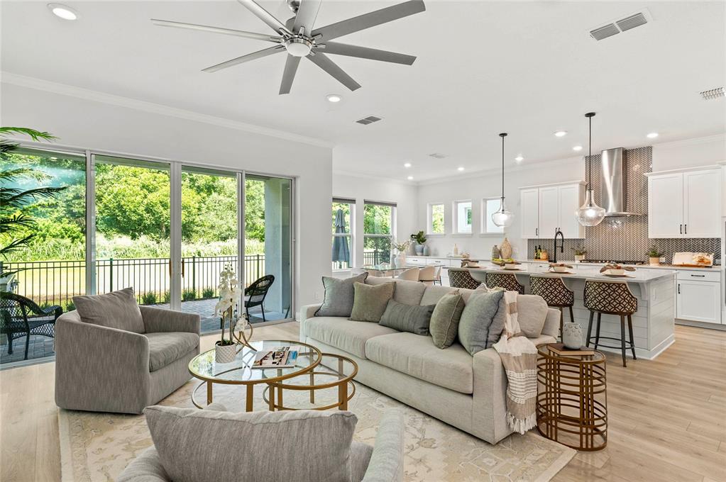 An open-concept living room and kitchen feature light wood floors, a large island, and patio — 570 WISHBONE LANE, LAKE MARY, FL