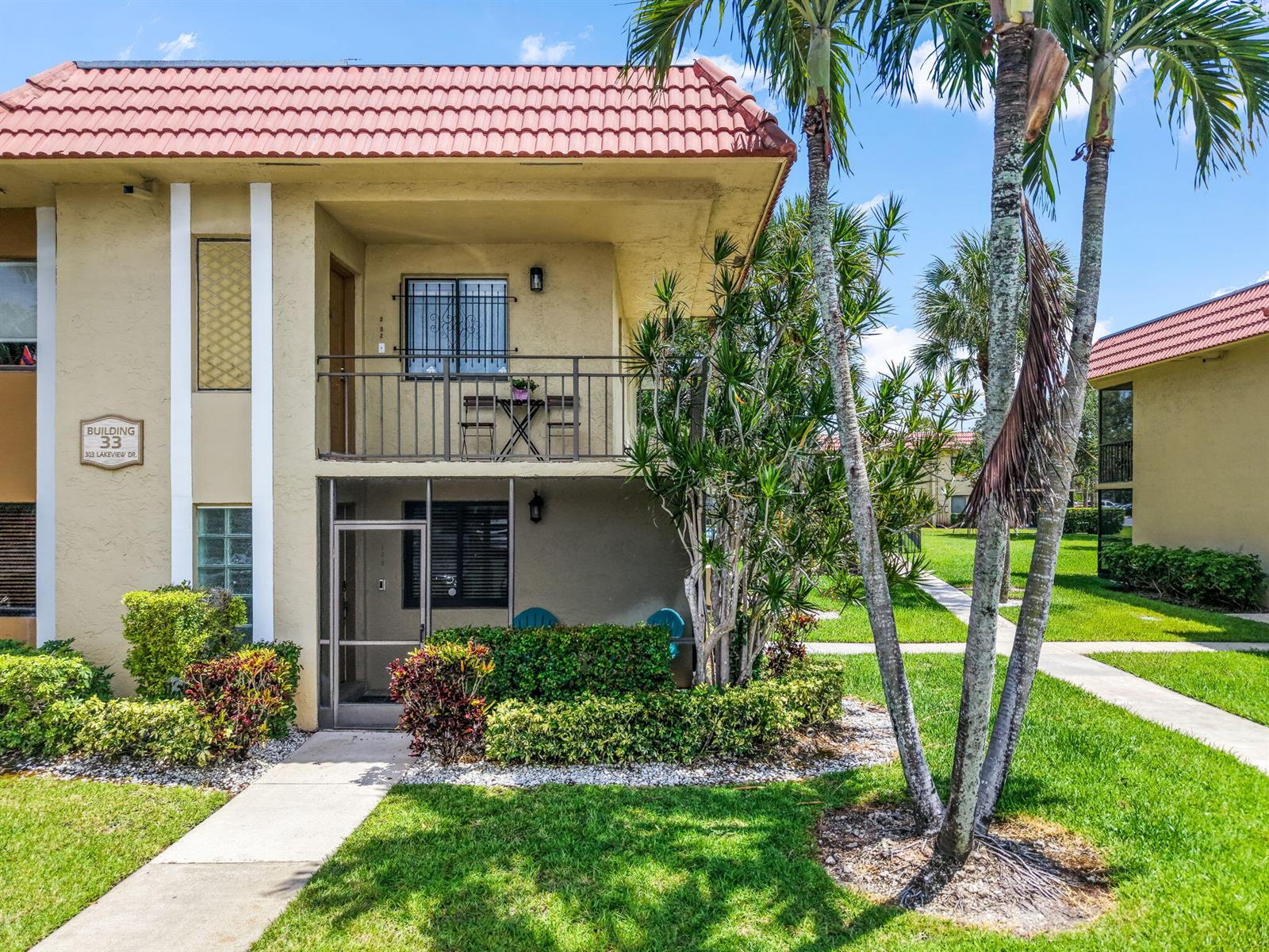 A two-story apartment building with a red tile roof, balconies, and landscaped grounds — 303 Lakeview Drive # 102, Weston FL 33326, WESTON, FL