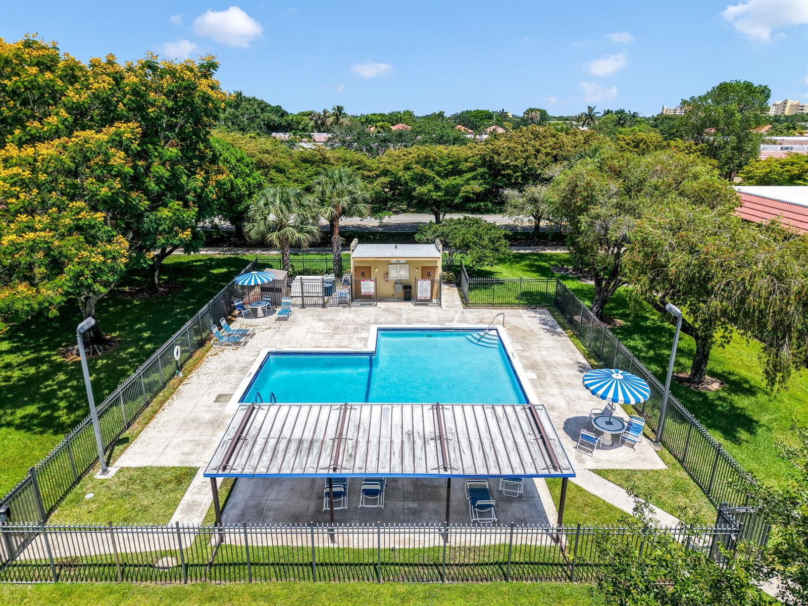 An aerial view of an outdoor swimming pool surrounded by a fence and trees — 303 Lakeview Drive # 102, Weston FL 33326, WESTON, FL