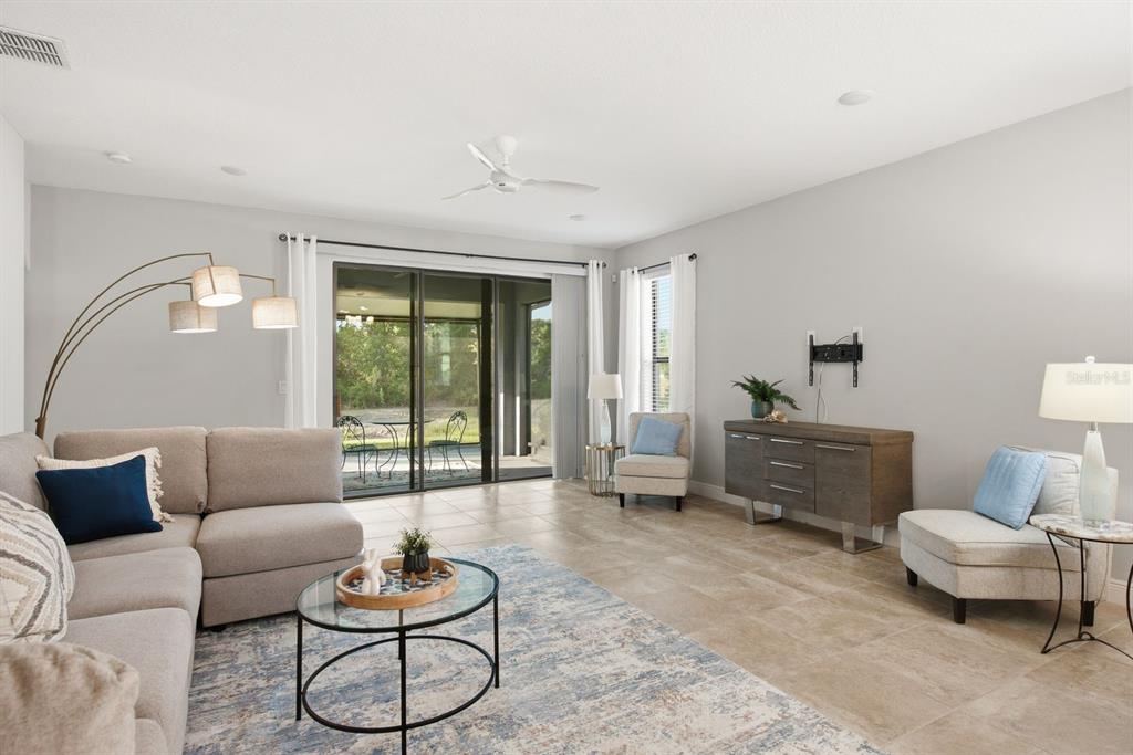A living room features tile floors, a sectional sofa, a glass coffee table, and sliding doors — 11392 WEAVER HOLLOW ROAD, NEW PORT RICHEY, FL