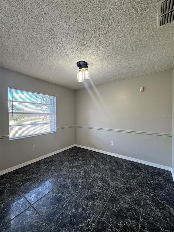 A room with gray walls, chair rail molding, dark marble-patterned tile floors, and a ceiling light — 721 GREENLEAF LANE, LAKE WALES, FL