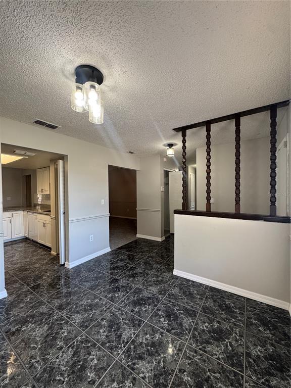 A dining area features dark marble-patterned tile flooring, a decorative spindle room divider, and lighting — 721 GREENLEAF LANE, LAKE WALES, FL