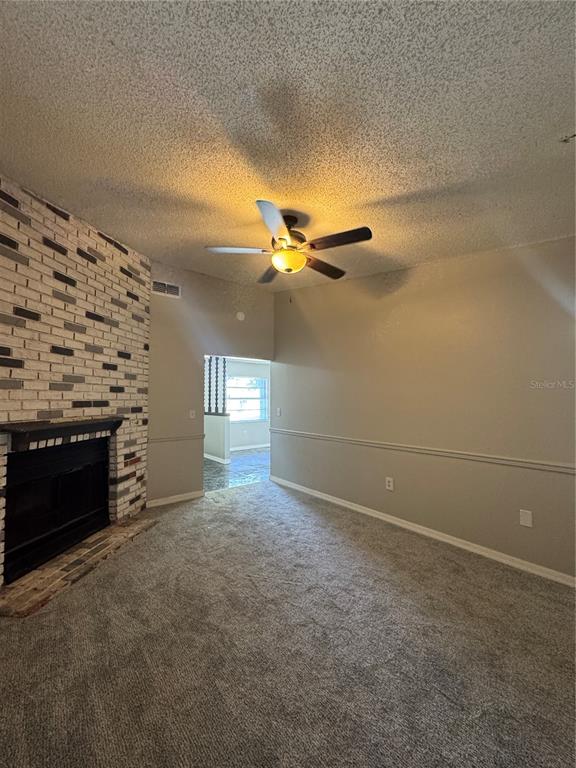 A living room features a brick fireplace, gray carpet, and a ceiling fan — 721 GREENLEAF LANE, LAKE WALES, FL