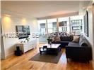 A living room features hardwood floors, a sectional sofa, a coffee table, and large windows — 8911 Collins Ave # 1104, Surfside FL 33154, SURFSIDE, FL