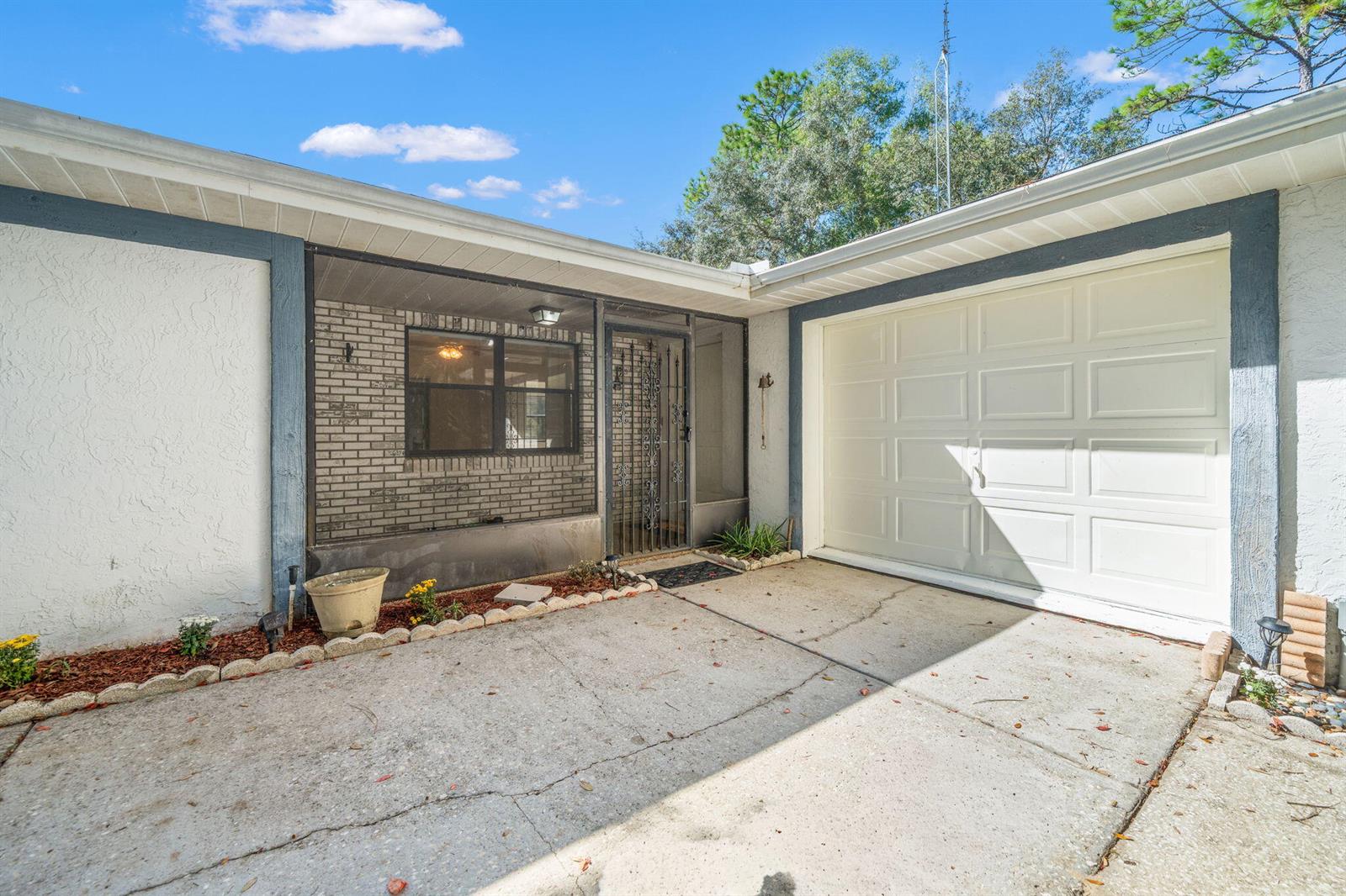 A concrete driveway leads to a white garage door and a screened-in entryway — 7418 N Firwood Circle, FL 34433, FL