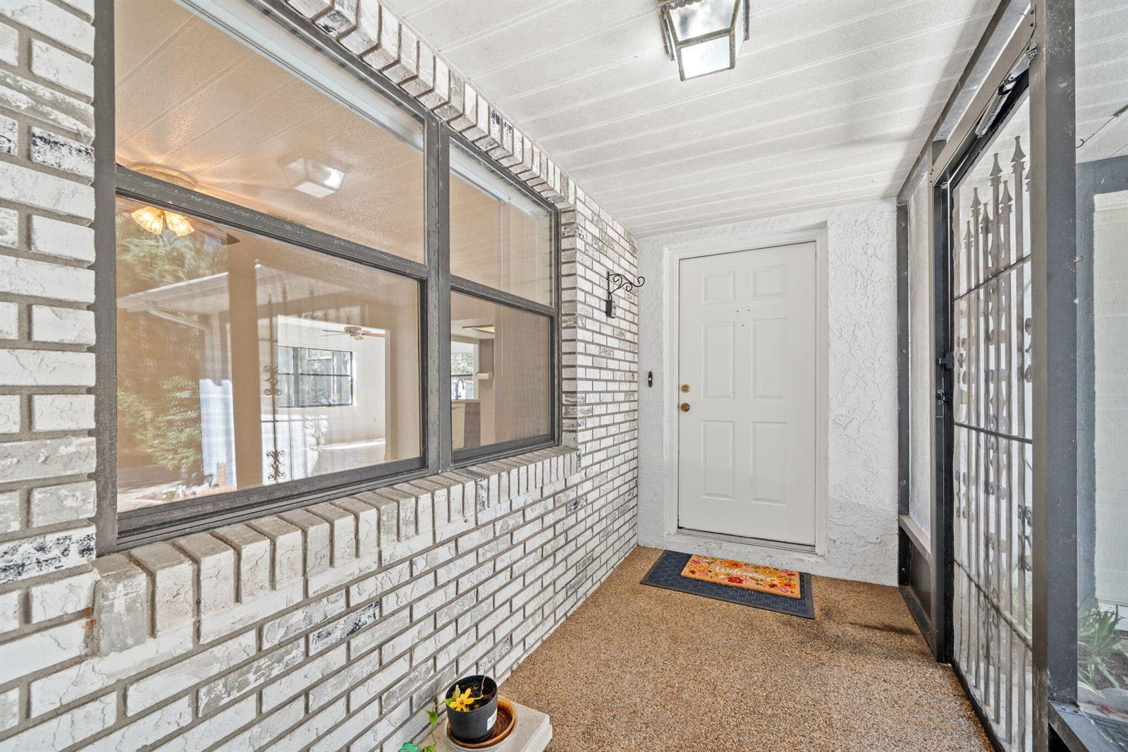 A covered brick entryway features a white front door, a screen door, and windows — 7418 N Firwood Circle, FL 34433, FL